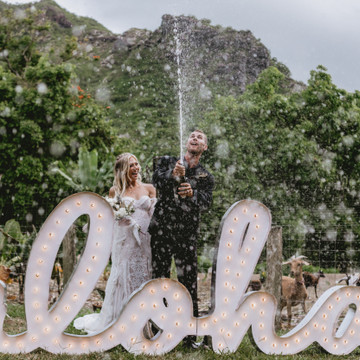 Abby + Nash spray champagne to celebrate with their furry goat friends. 
North Shore - Oahu. Hawaii!

Planner: @vidachicevents
Cake:@bakewithaloha
Rentals: @alohaartisans
Gown: @Magnoliawhite_hawaii
Hair and Makeup: @lovebylaur
Linens and table settings: @theweddinglinenco
Tap Truck: @alohataps 
Flowers: @vidachicevents 
Couple: @nashhagen + @abby_hawaii
Aloha marquee sign: @designed_with_aloha
Rings: @theweddingringshop